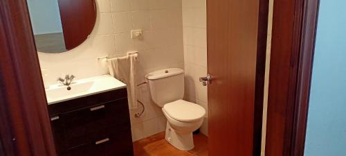 a bathroom with a toilet and a sink and a mirror at CASA EN PLAYA DE RAZO CON JARDIN Y VISTAS AL MAR in Razo