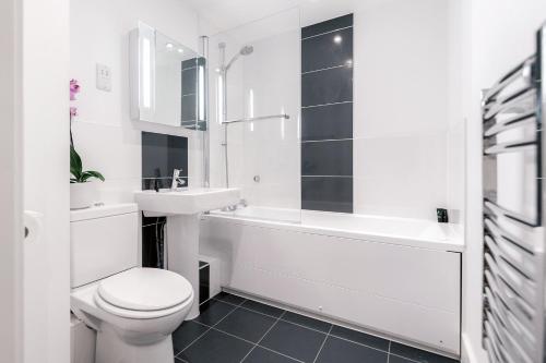 a white bathroom with a toilet and a sink and a tub at Roomspace Serviced Apartments - Capitol Square in Epsom