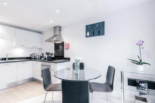 a white kitchen with a table and chairs in it at Roomspace Serviced Apartments - Capitol Square in Epsom