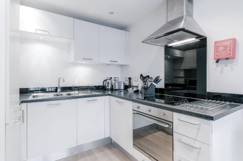 a kitchen with white cabinets and a stove top oven at Roomspace Serviced Apartments - Capitol Square in Epsom