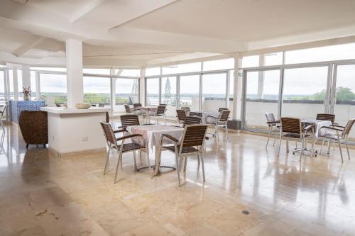 een eetkamer met tafels, stoelen en ramen bij PlazaMar Pacifico Hotel in Buenaventura