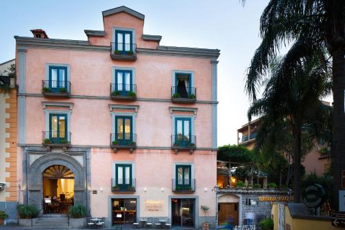 un grand bâtiment rose avec des fenêtres et des plantes dans l'établissement Palazzo Marziale, à Sorrente