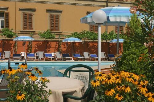 a table with an umbrella next to a swimming pool at Grand Hotel Plaza & Locanda Maggiore in Montecatini Terme