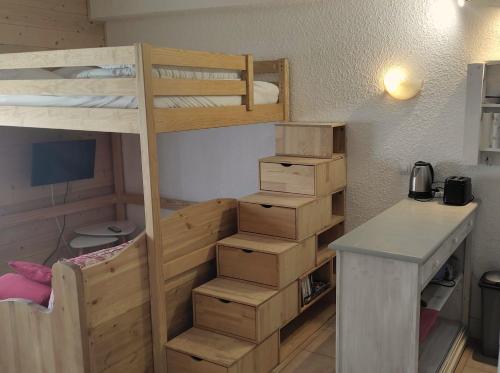 a room with a bunk bed and a desk with boxes at Studio des Jeux - Alpe d'Huez Hyper Centre - 4-5 personnes - Wifi in LʼHuez