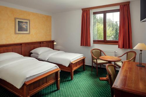 a room with two beds and a table and chairs at Golf & Spa Kunětická Hora in Dritec