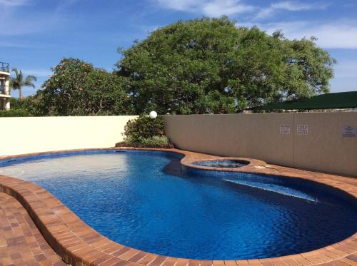 a swimming pool in a backyard with a fence and trees at Kirribilli Apartments in Brisbane