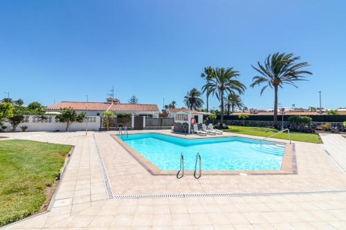 a swimming pool in a yard with palm trees at Beach Luxury Bungalow in San Bartolomé de Tirajana