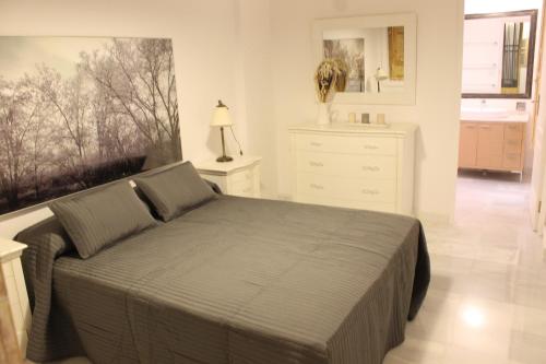 sypialnia z łóżkiem i białą komodą w obiekcie Amazing Sevilla Apartamento w Sewilli