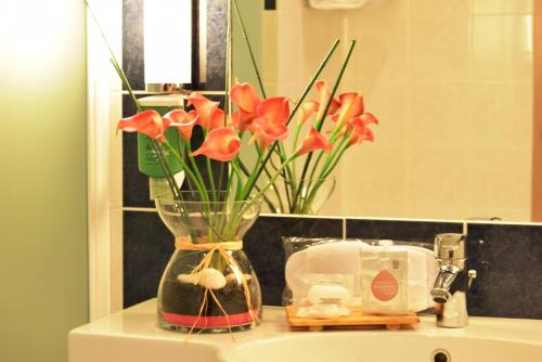 a vase with flowers on top of a bathroom sink at Kyriad Prestige - Bordeaux Aeroport in Mérignac