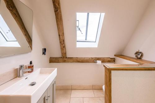 baño con lavabo y 2 ventanas en Granary Barn Snape Air Manage Suffolk en Saxmundham