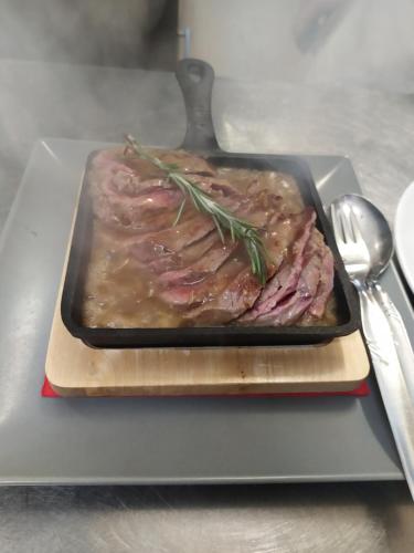 a tray of meat with rosemary on top of it at Albergo Ristorante Cacciatori in Auronzo di Cadore