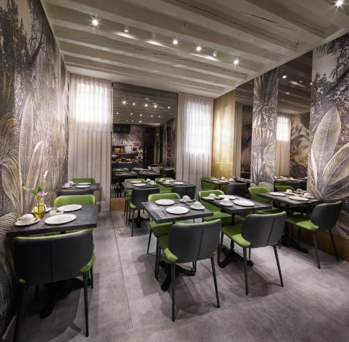 um restaurante com mesas e cadeiras verdes numa sala em Hotel Orsaria em Veneza