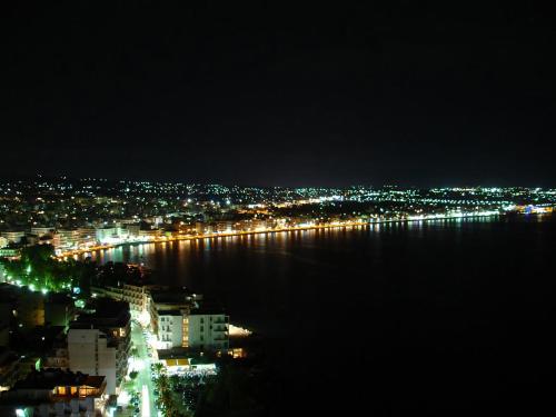 a view of a city at night with the water at Luxurious apartment in the heart of town ! in Loutraki