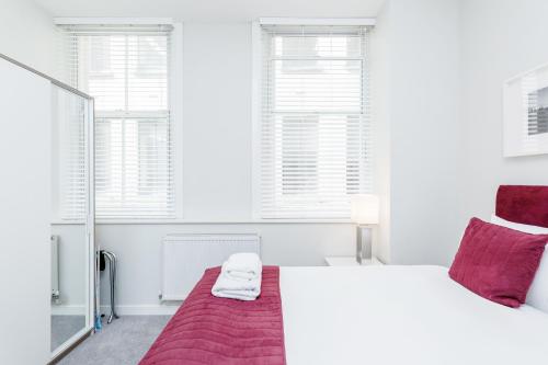 a white bedroom with a bed and two windows at Roomspace Serviced Apartments - Sterling House in London