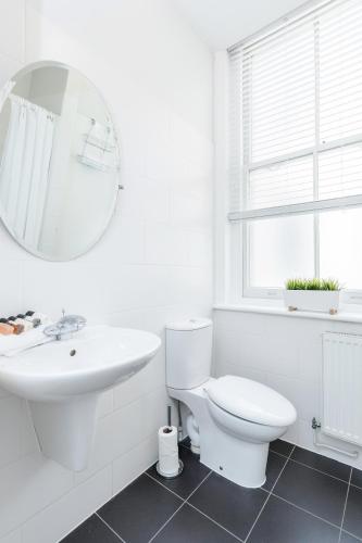 a white bathroom with a toilet and a sink at Roomspace Serviced Apartments - Sterling House in London