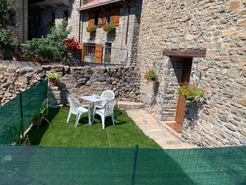 a patio with a table and chairs in front of a building at La Casita de Ordesa in Frajén