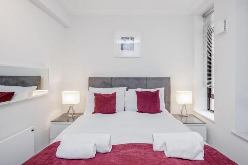 una camera da letto con un grande letto bianco con cuscini rossi di Roomspace Serviced Apartments - River House a Londra