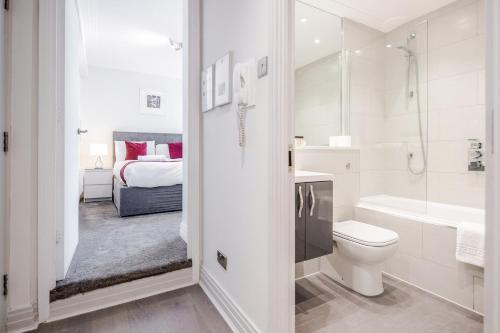 ロンドンにあるRoomspace Serviced Apartments - River Houseの白いバスルーム(トイレ付)、ベッド1台が備わります。