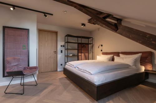 a bedroom with a large bed and a chair at Wailtl Hotel in Dorfen