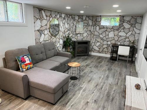 a living room with a couch and a stone wall at Adorable 1 Bedroom Suite With Kitchen Fireplace in Cambridge