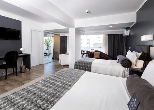 um quarto de hotel com duas camas e uma secretária em Hotel Sibara SPA & Convenções no Balneário Camboriú