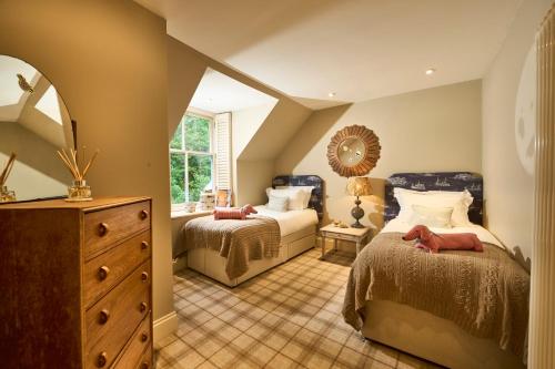 a bedroom with two beds and a dresser and a mirror at Hazelbank, sleeps 10, on the shores of Loch Fyne in Cairndow