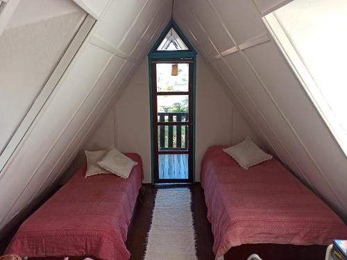 2 camas num quarto no sótão com uma janela em Casa de campo, charme e aconchego em cond. fechado em Atibaia
