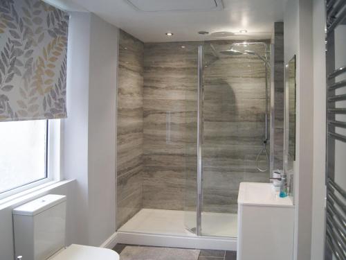 uma casa de banho com um chuveiro e uma porta de vidro em Kiwi Corner em Amble