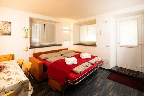 een slaapkamer met een bed met rode lakens en 2 ramen bij Appartamento Dragorosa Livigno in Livigno