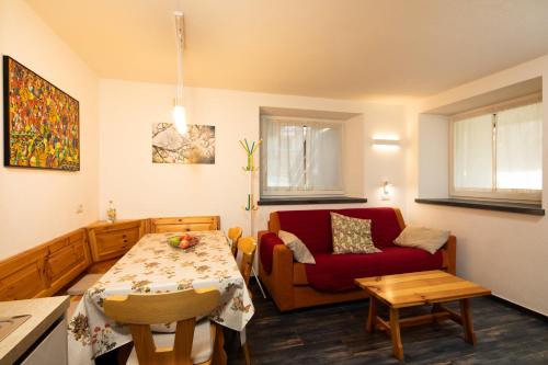 een woonkamer met een tafel en een rode bank bij Appartamento Dragorosa Livigno in Livigno