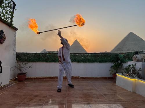a man is holding up a pole with fire at Pyramids Top Inn in Cairo