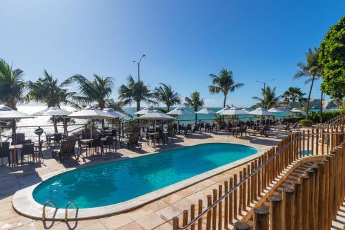 a swimming pool with tables and chairs and umbrellas at Praiamar Natal Hotel & Convention in Natal