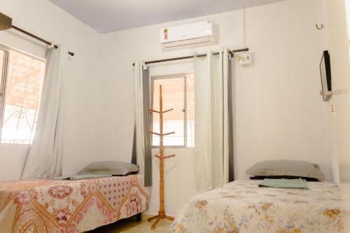 um quarto branco com 2 camas e uma janela em Linda Casa c Wi-Fi a 900m da Praia de Itatinga MA em Alcântara