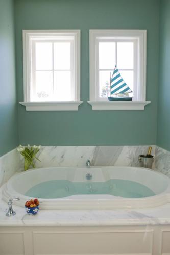 a bath tub in a bathroom with two windows at West Cliff Inn, A Four Sisters Inn in Santa Cruz