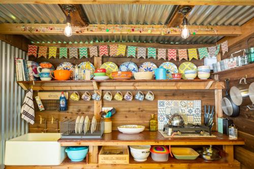 a kitchen with wooden shelves filled with bowls and utensils at Orion 4-Person Stunning Lotus Belle Tent in Ross on Wye
