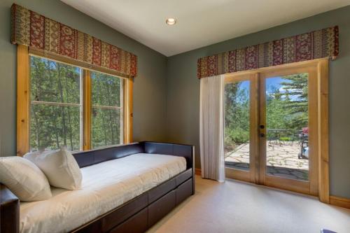a bedroom with a bed and two large windows at Ski Tip by Summit County Mountain Retreats in Keystone