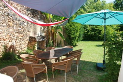 - une table, des chaises et un parasol dans la cour dans l'établissement Maison spacieuse au cœur de Queyssac avec jardin, à Queyssac