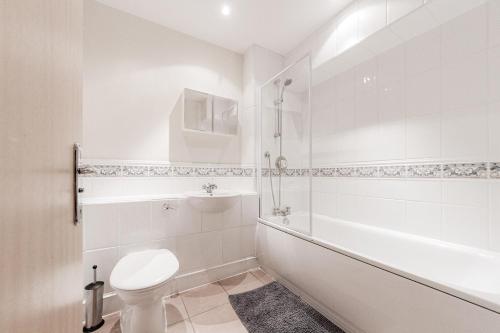 a white bathroom with a toilet and a bath tub at Roomspace Serviced Apartments - Cascades Court in London