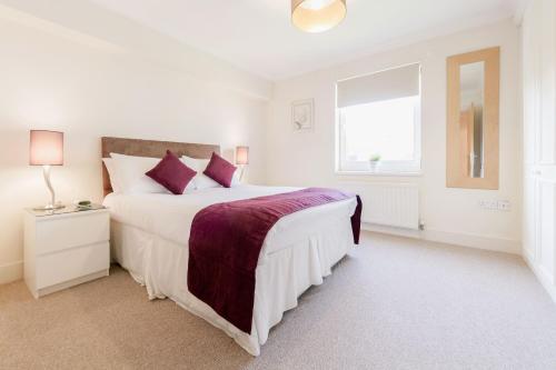 a white bedroom with a large bed and a window at Roomspace Serviced Apartments - Cascades Court in London