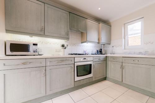 uma cozinha com armários brancos e um micro-ondas em Roomspace Serviced Apartments - Cascades Court em Londres