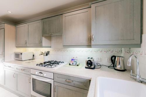uma cozinha com armários brancos e um forno com placa de fogão em Roomspace Serviced Apartments - Cascades Court em Londres