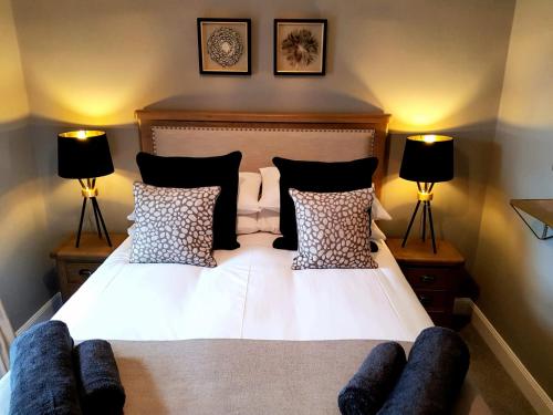 een bed met zwart-witte kussens en 2 lampen bij Glencoe House Inverness in Inverness