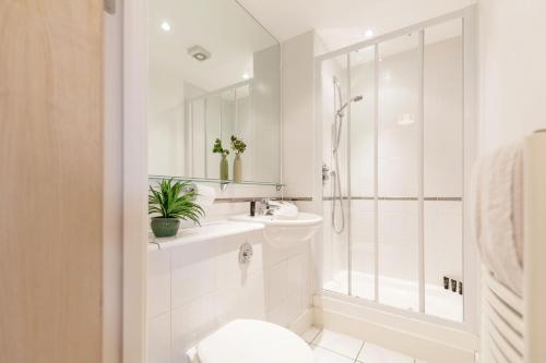 baño blanco con ducha y lavamanos en Roomspace Serviced Apartments - Central Walk, en Epsom