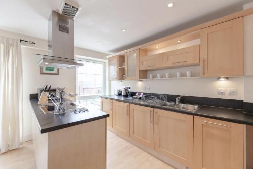 una cocina con armarios de madera y encimeras negras en Roomspace Serviced Apartments - Central Walk, en Epsom