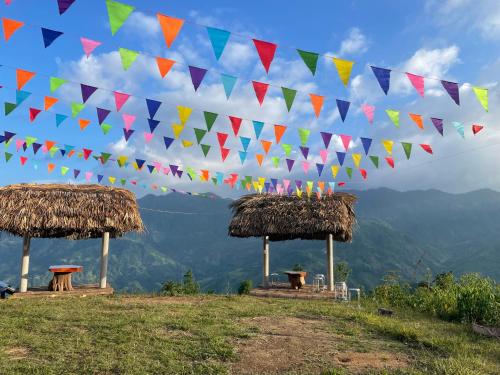 a row of flags on a hill with huts at Homestay Chân Mây Chiêu Lầu Thi in Hoàng Su Phì