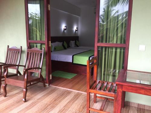 ヒッカドゥワにあるSerenade Beach Hotelのベッド1台、椅子2脚、鏡が備わる客室です。