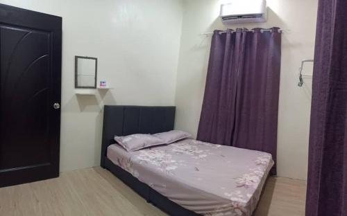 niewielka sypialnia z łóżkiem i fioletowymi zasłonami w obiekcie Ainaz Homestay Balik Pulau w mieście Balik Pulau