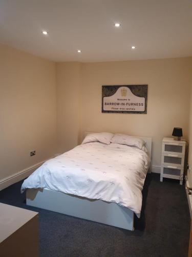 a bedroom with a bed and a sign on the wall at Spacious 2 bed appartment next to BAE with spa bath in Barrow in Furness