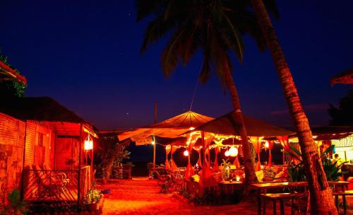 a restaurant with tables and umbrellas at night at Sonho do Mar in Agonda