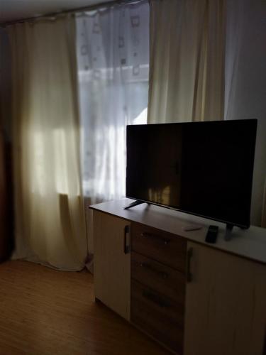 TV de pantalla plana en un tocador frente a una ventana en Cazare, en Deva